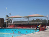 Outdoor pool with people swimming and a large USA Shade Tri-Truss Cantilever with 'Diablos' branding.