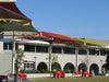 Outdoor seating area with red and green USA Shade Tri-Truss Cantilevers and benches in front of a building.