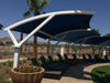 Outdoor seating area with blue USA Shade Panorama Cantilever and lounge chairs under a clear blue sky.