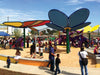 Colorful playground with USA Shade Flower Shade Structure and children playing on a sunny day.