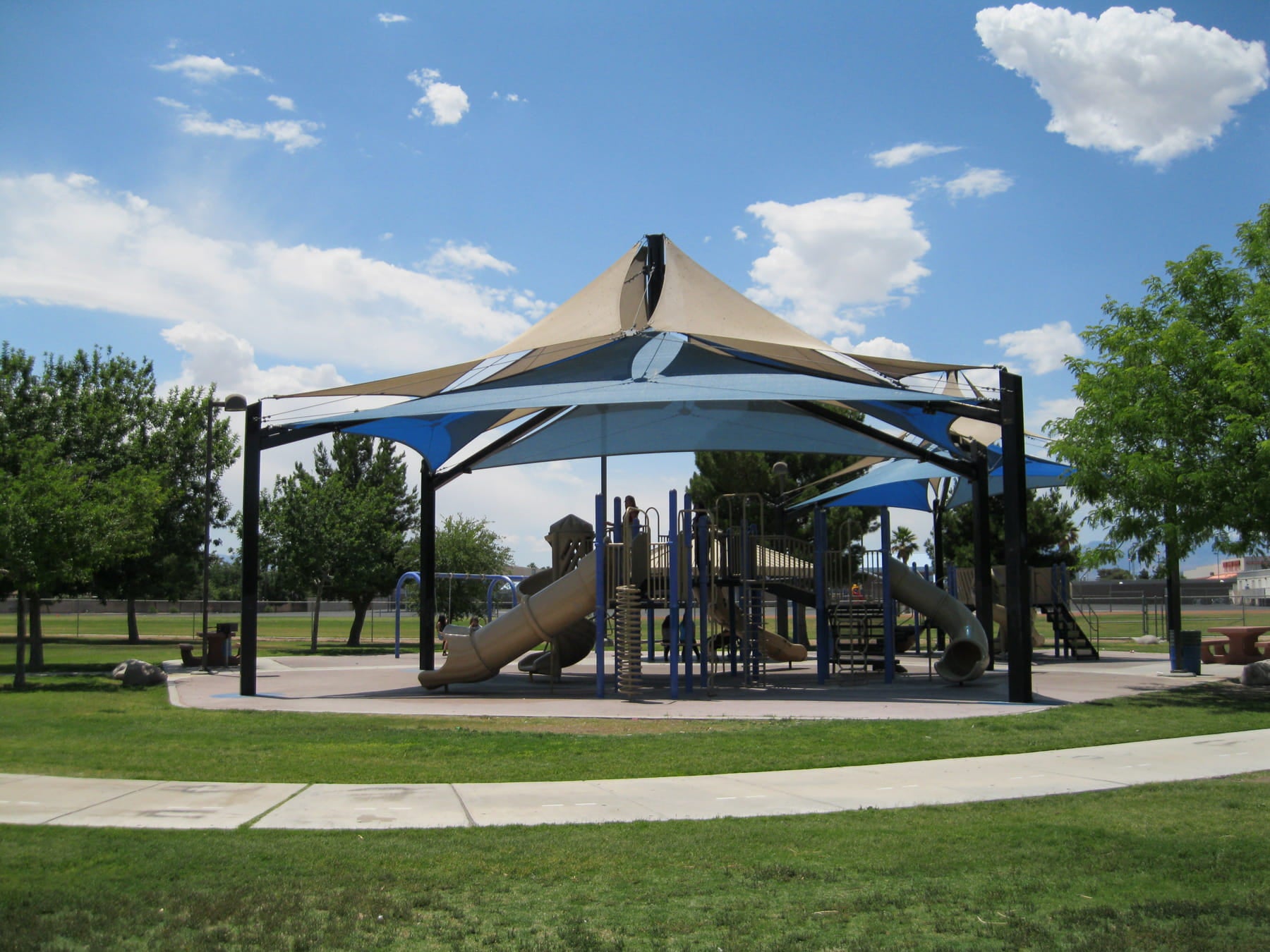 Playground with a large USA Shade Multi-Layer Super Span Pyramid Shade in a park setting