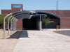 USA Shade Cantilever Arch Walkway Covered walkway leading to a building with a blue sign on a clear day.