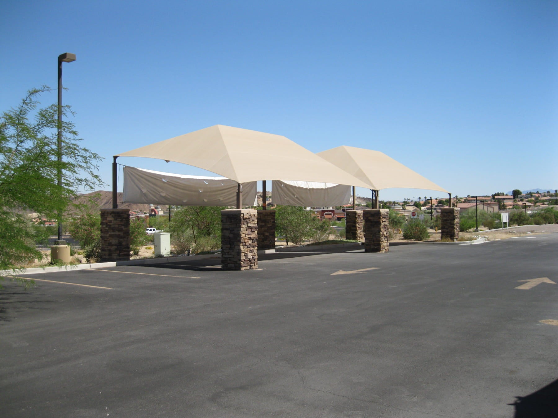 Large beige USA Shade Slant Hip over a parking area with clear blue sky.