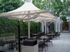 Outdoor seating area with large USA Shade 4-point Twilite Umbrellas and tables under a canopy