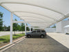 Car parked under a white USA Shade Full Arch Cantilever with trees and a building in the background