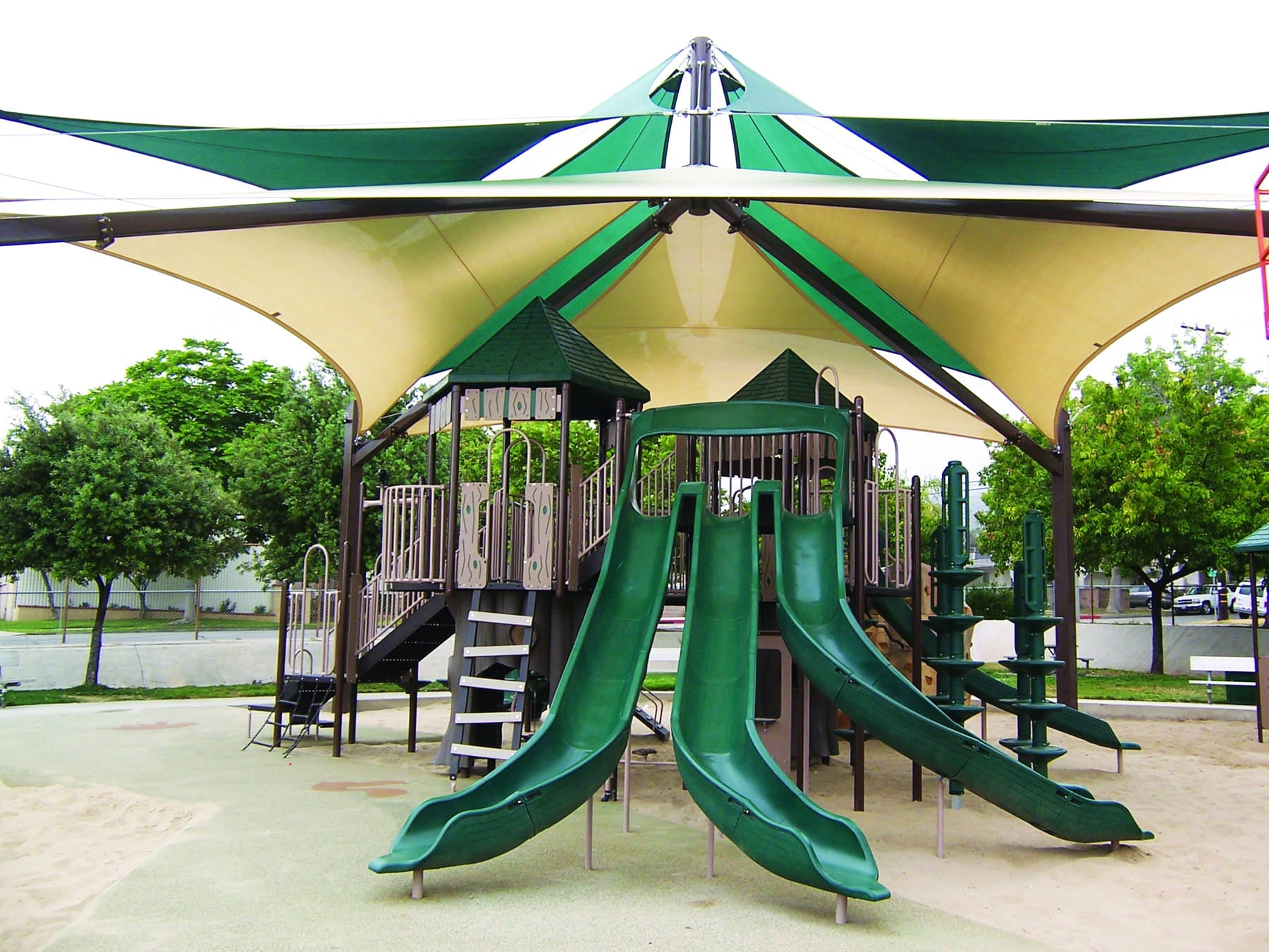 Children's playground with green slides and a large USA Shade Multi-Layer Super Span Pyramid Shade