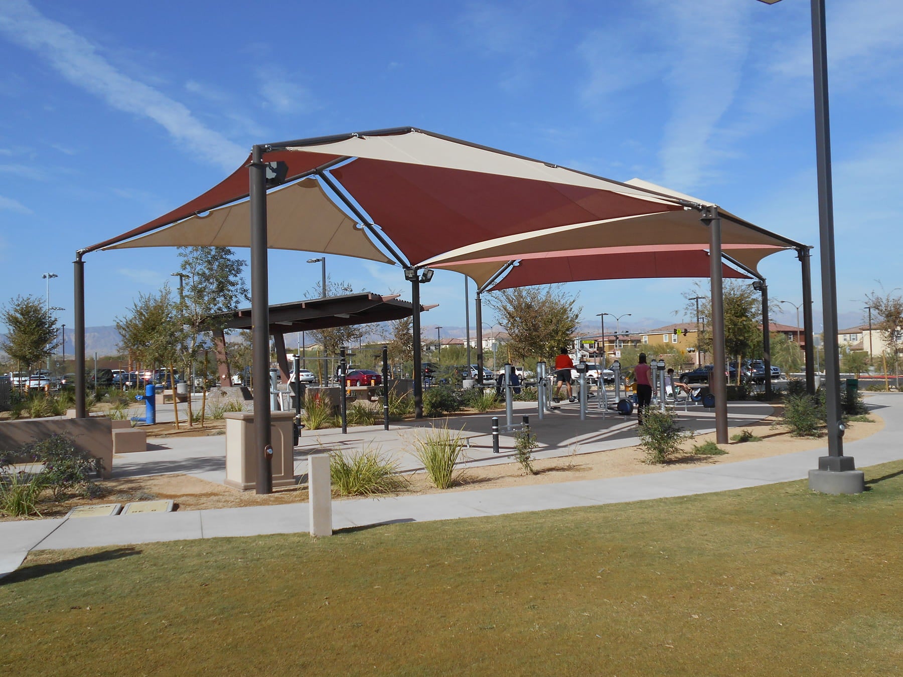 Pavilion with red and beige USA Shade Multi-Panel Hip in a park setting