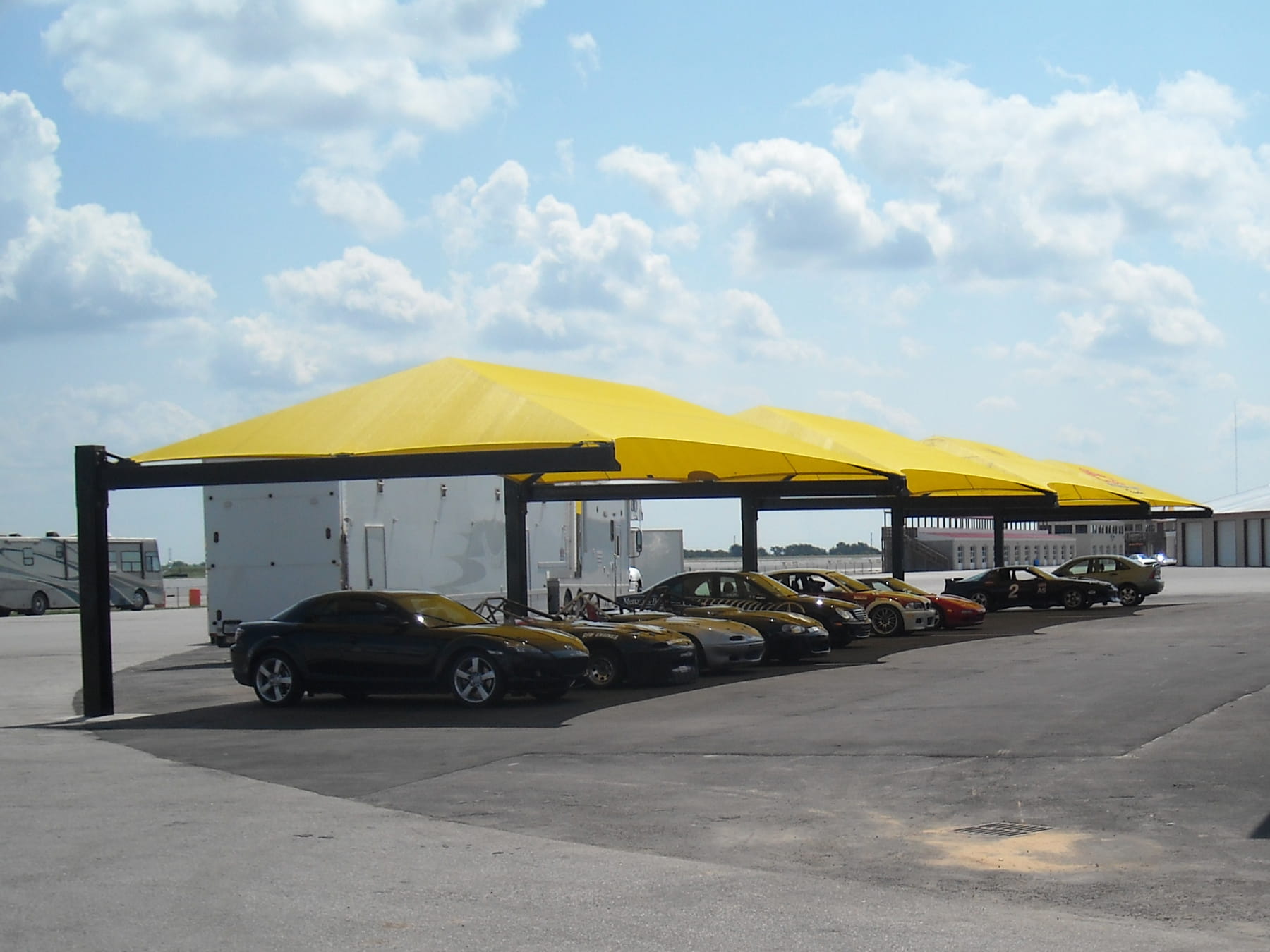 Row of cars under yellow USA Shade Full Hip Cantilever Shades on a clear day