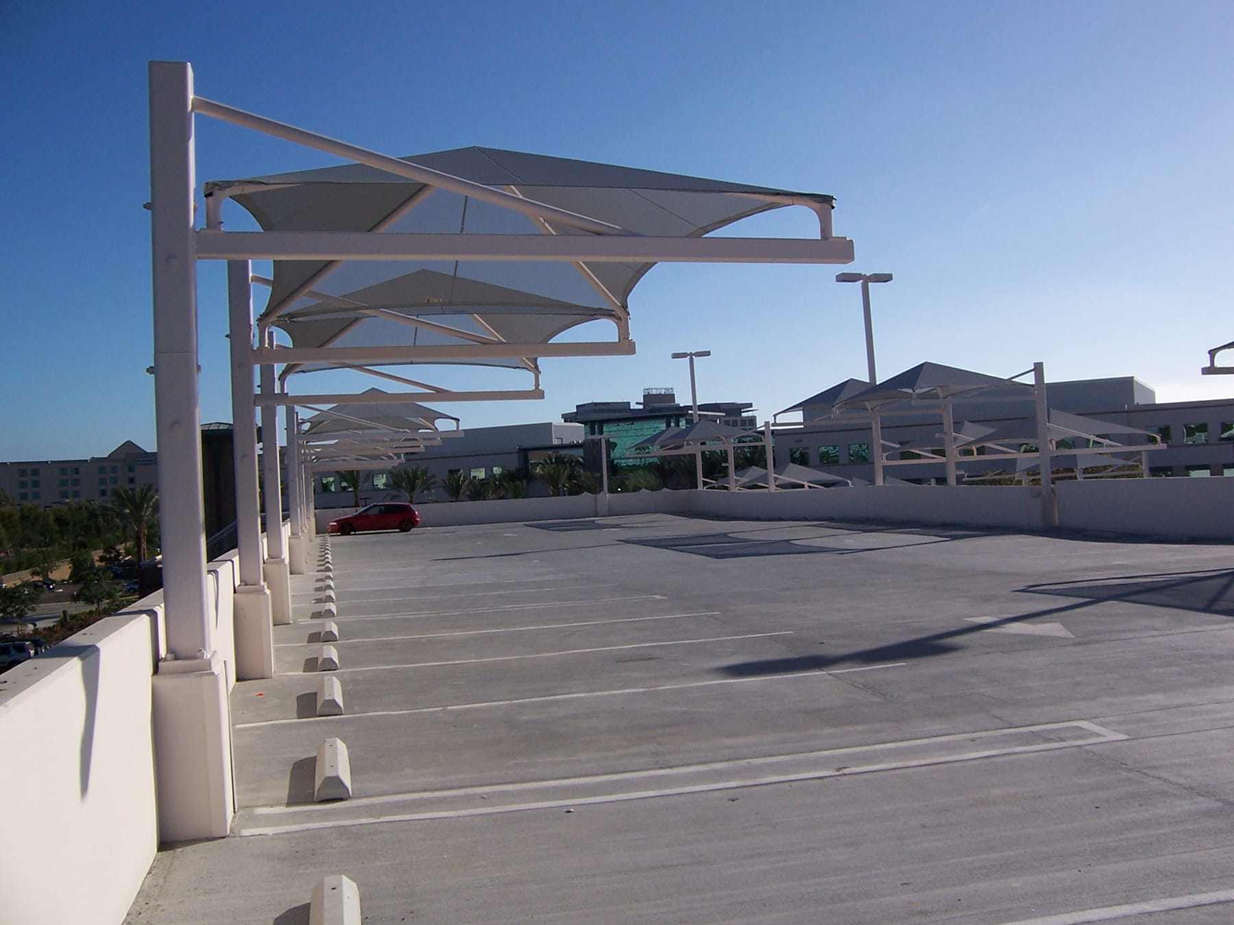 Parking lot with white USA Shade Tri-Truss Cantilever shade structures on a clear day
