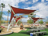 Outdoor picnic area with USA Shade Pegasus Shade structures, tables, and benches under a blue sky.