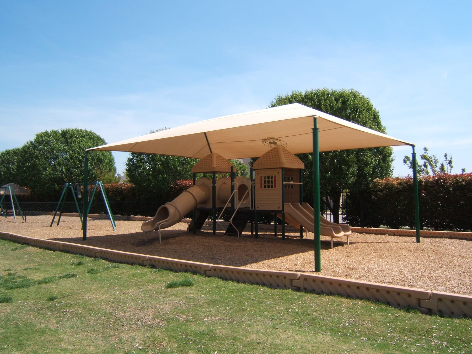 Playground with a USA Shade Hip providing shade on a sunny day.