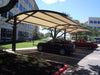 Car parked under a USA Shade Panorama Cantilever in a parking lot with a building in the background