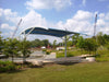 USA Shade Panorama Cantilever with a blue roof in a park setting under a cloudy sky
