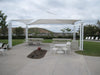 Outdoor patio area with a USA Shade Multi-Panel Pyramid, tables, chairs, and benches on a cloudy day.