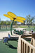 Children playing at a playground with a large yellow USA Shade Flower Shade Structure.