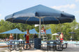 Large blue USA Shade Coolbrella over a poolside area with people and tables.