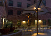 Outdoor patio area with tables, chairs, and USA Shade Aquarius Shade at night.