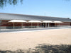 Building exterior with large white USA Shade Two Post Hip Shade Structures and a clear blue sky.