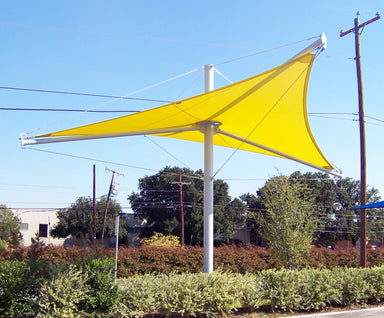 Yellow USA Shade Aurora Shade sail attached to a pole with power lines and trees in the background