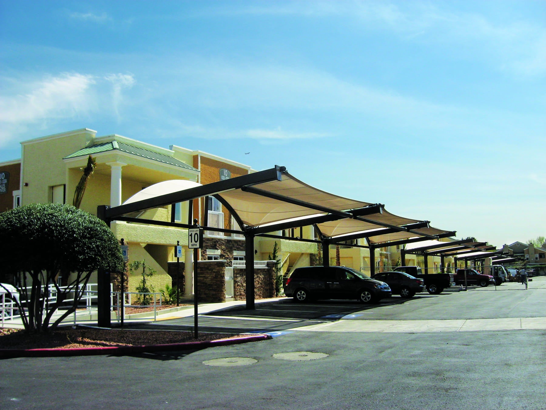 Commercial building with outdoor USA Shade Cypress Cantilevers and parked cars on a clear day