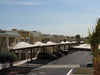 Parking lot with USA Shade Cypress Cantilevers, cars and a building in the background under a clear blue sky.
