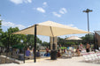 Beige USA Shade Pyramid Shade providing shade at a poolside area with people sitting underneath.