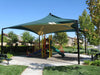 Children's playground with green USA Shade Mariner Pyramid Shade and slide in a park setting