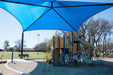 Children's playground with blue USA Shade Sahara Shade and slide in a park setting