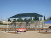 Outdoor sports facility with a green USA Shade Slant Hip and bleachers under a clear blue sky.